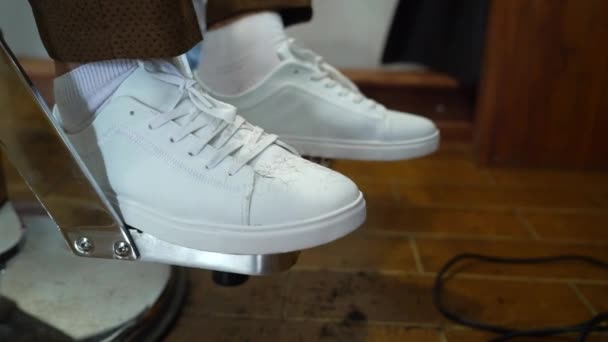 Hombre en zapatos blancos zapatillas de deporte sentado en la barbería — Vídeos de Stock