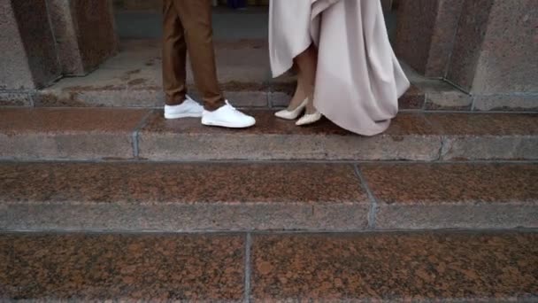 Bride and groom walking in a city at rainy cloudy day. Center of european town. Newlyweds going on a street, dress waving in slowmotion — Stock Video
