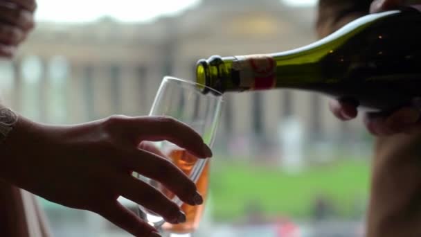 Despeje champanhe rosa ou vinho espumante em copo de garrafa. Cidade europeia em segundo plano . — Vídeo de Stock