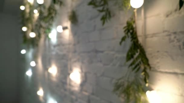 전나무와 흰색 벽돌 벽에 매달려 장식 실내 문자열 조명 — 비디오