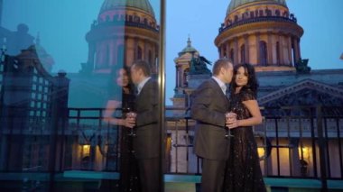 Genç caucasican erkek takım elbise ve balkon bir şehirde kalan siyah lüks içinde seksi esmer kadın