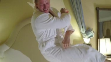 Genç seksi çift yatak beyaz bornoz içinde döşeme ve having fun geceleri. Gülümseyen ve laughting