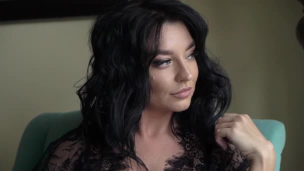 Wanita muda seksi berambut cokelat duduk di kursi di kamar tidur dan berpose . — Stok Video
