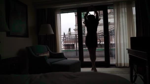 Giovane donna bruna sexy in lingerie che rimane in camera da letto vicino alla finestra e posa . — Video Stock