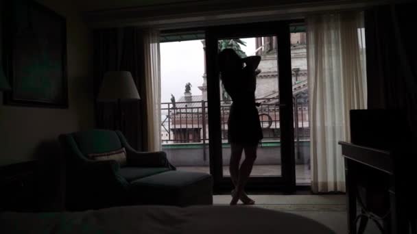 Giovane donna bruna sexy in lingerie che rimane in camera da letto vicino alla finestra e posa . — Video Stock