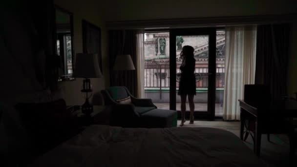 Jonge sexy brunette vrouw in lingerie verblijft in slaapkamer in de buurt van venster en poseren. — Stockvideo