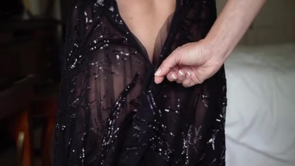 Young sexy brunette woman in black luxury dress staying in bedroom near window and undressing. — Stock Video