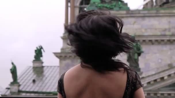 Молодая сексуальная брюнетка в черном роскошном платье, стоящая на балконе в городе — стоковое видео
