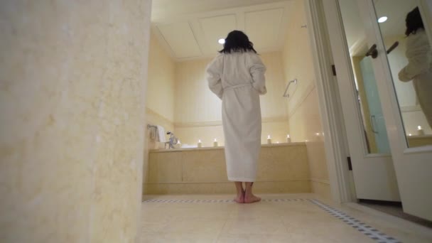 年轻性感的黑发女人去洗手间, 脱衣服脱浴衣和铺设在浴缸. — 图库视频影像