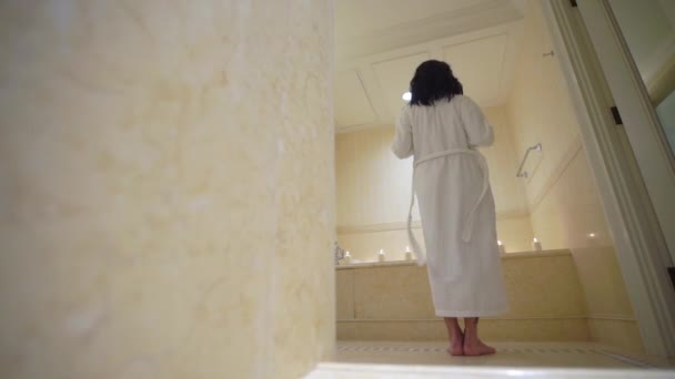 Νέοι σέξι μελαχρινή γυναίκα πηγαίνει τουαλέτα, Γδύσιμο, αφαίρεση μπουρνούζι και τοποθέτηση στην μπανιερα. — Αρχείο Βίντεο