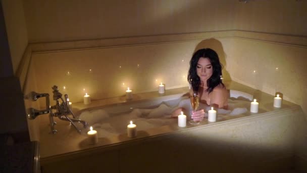 Молода сексуальна брюнетка йде у ванну, роздягається, знімаючи халат і лежачи у ванній . — стокове відео