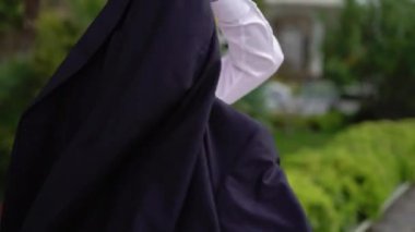 Genç bir adam açık havada siyah ceket koyar