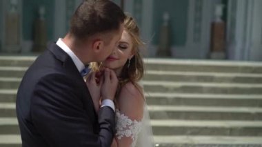 Genç gelin ve damat bir şehirde poz. Peçe rüzgarlı yaz gününde sallayarak.