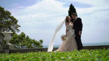 Genç güzel gelin gelinlik ve sarılma ve öpüşme açık havada damat. Deniz kenarında yeni evliler.