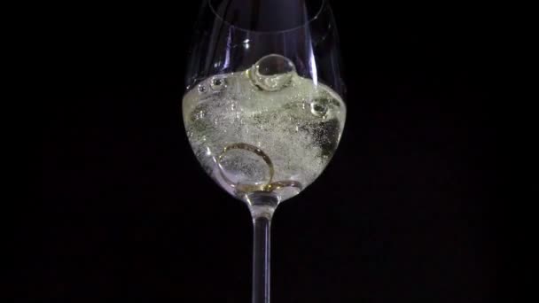 Två vigselringar i glas champagne super slowmotion — Stockvideo