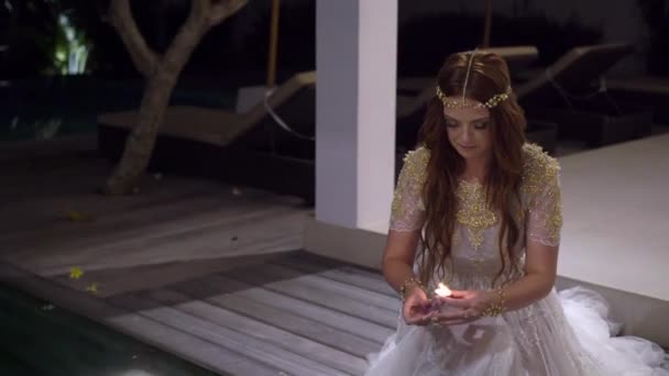 Jeune belle mariée avec bougie la nuit près de la piscine à la villa — Video