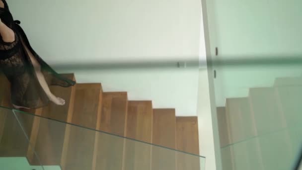 Молодая сексуальная рыжеволосая женщина в черном белье спускается вниз по лестнице — стоковое видео