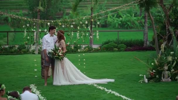 Bruden och brudgummen vid vigseln. Tropisk trädgård på kvällen. Härlig nygifta par — Stockvideo
