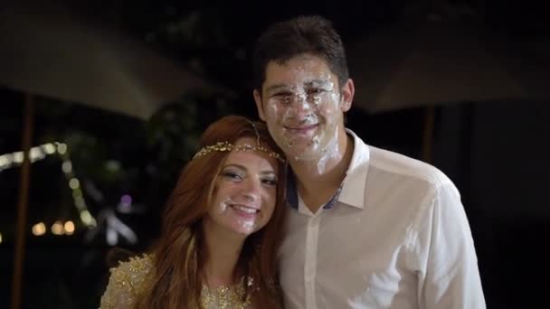 Girl smears a piece of wedding cake on the face of the groom. The celebration of the wedding. — Stock Video