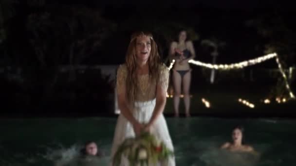 La mariée lance un bouquet au mariage. Fête de piscine la nuit — Video