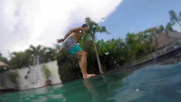 En ung mand hopper i poolen. Tropisk Villa fest i sommer. Ferie – Stock-video