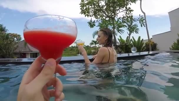 Young lovely couple clinking glasses in the swimming pool at tropical vacation villa. — Stock Video