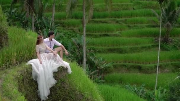新婚夫妇坐在巴厘岛的稻田露台上摆姿势。牵手, 拥抱。浪漫婚礼. — 图库视频影像