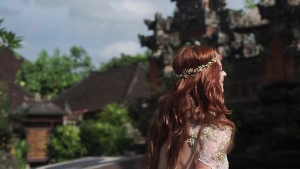 バリ島の寺院の近くを実行して美しい花嫁。近くを歩いてください。ロマンチックな結婚式. — ストック動画