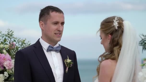 結婚式で新郎新婦 愛の若いカップルは アーチに立っています 海で結婚式 — ストック動画