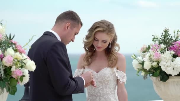 Bruden och brudgummen vid vigseln. Ett ungt par i kärlek står på bågen. Bröllop vid havet — Stockvideo