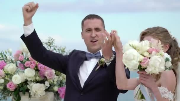 Los novios en la ceremonia de la boda. Una joven pareja enamorada está en el arco. Boda junto al mar — Vídeo de stock