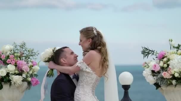 Gli sposi alla cerimonia nuziale. Una giovane coppia innamorata si trova all'arco. Matrimonio al mare — Video Stock