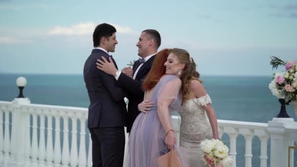 Guests at the wedding congratulate the bride and groom at the wedding ceremony. A young couple in love stands at the arch. Wedding by the sea — Stock Video