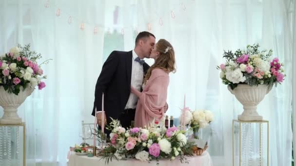 Nevěsta a ženich líbat na svatební hostině. Mladá milující svatební pár v stanu — Stock video