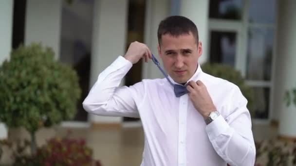 Un jeune homme met un noeud papillon bleu — Video