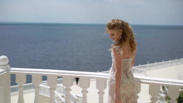 Молодая невеста стоит и позирует на балконе. Свадьба у моря — стоковое видео