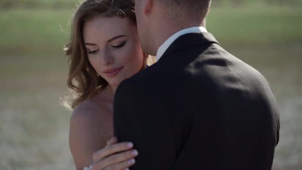 Νέοι όμορφη νύφη σε ένα νυφικό και ο γαμπρός αγκάλιασμα και το φίλημα — Αρχείο Βίντεο
