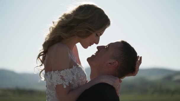 Ung vakker brud i brudekjole og brudgom som klemmer og kysser – stockvideo