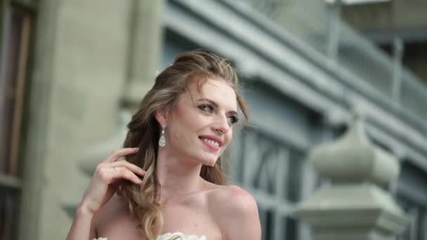 Junge Braut posiert in einer Stadt. Schleier wehen an windigen Sommertagen. — Stockvideo