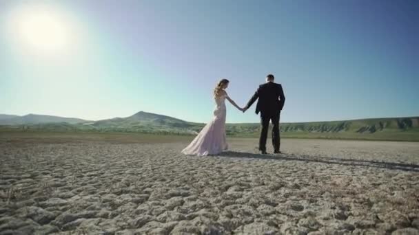 Jonge mooie bruid in een bruidsjurk en de bruidegom lopen — Stockvideo