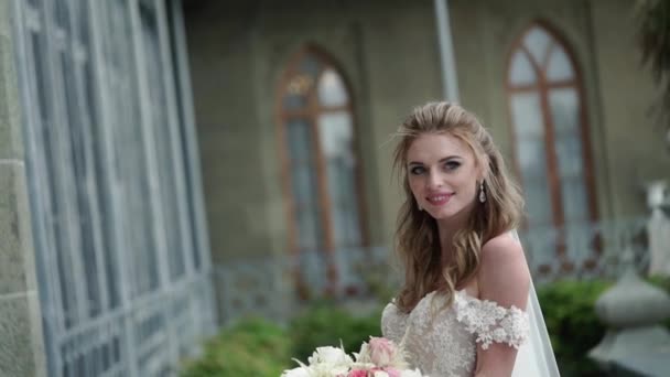 Young bride posing in a city. Waving veil at windy summer day. — Stock Video