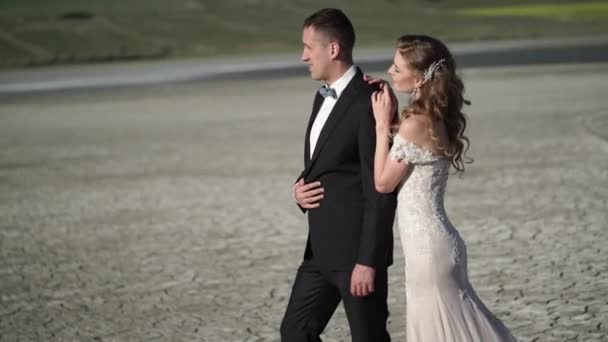 Jovem noiva bonita em um vestido de noiva e noivo abraçando e beijando — Vídeo de Stock
