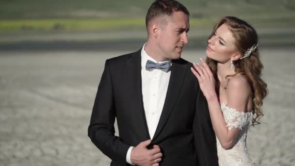 Unga vackra bruden i en bröllopsklänning och brudgummens kramar och kyssar — Stockvideo