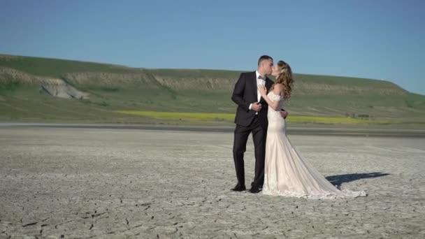 Mladá krásná nevěsta svatební šaty a ženich objímání a líbání — Stock video