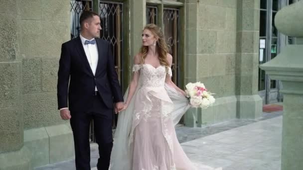 Unga vackra bruden i en bröllopsklänning och brudgummens promenader — Stockvideo