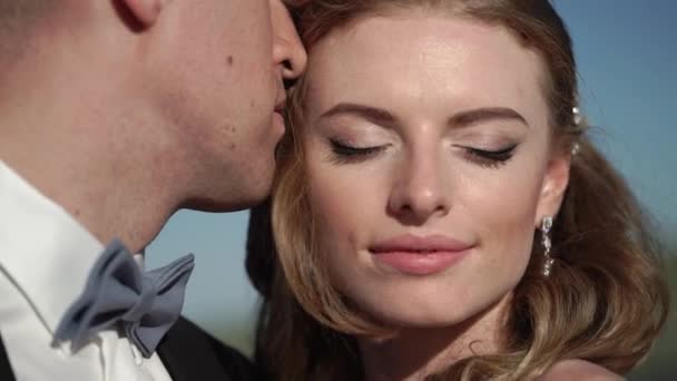 Fiatal gyönyörű menyasszony, menyasszonyi ruha és a vőlegény, átölelve és megcsókolta — Stock videók