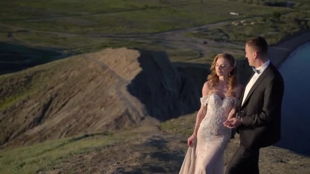 Novia y novio caminando en la montaña al atardecer — Vídeos de Stock