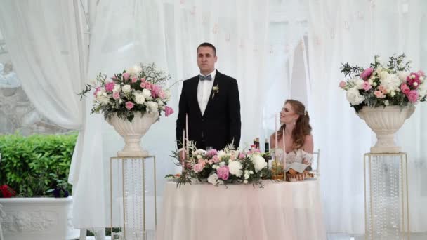 Жених и невеста веселятся на свадебном банкете. Молодая любящая супружеская пара в палатке — стоковое видео