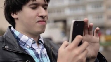 Genç adam sokağın eğleniyor onun kız arkadaşı cep telefonunuzda fotoğraf çekmek
