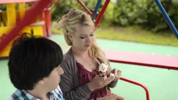 Joven pareja encantadora en columpios comiendo helado y divertirse — Vídeos de Stock